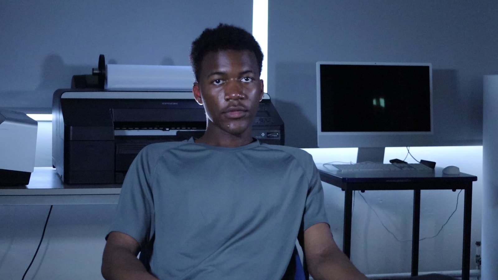 Actor at a desk under cool blue lighting